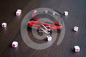 Pair bracelets in black and red with infinity. Handmade woven bracelets. Handmade decorations. Background with beads with hearts