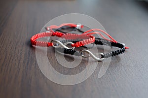 Pair bracelets in black and red with infinity. Handmade woven bracelets. Handmade decorations. Background with beads with hearts