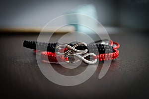 Pair bracelets in black and red with infinity. Handmade woven bracelets. Handmade decorations. Background with beads with hearts