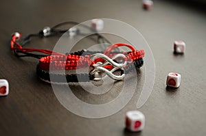 Pair bracelets in black and red with infinity. Handmade woven bracelets. Handmade decorations. Background with beads with hearts