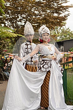 a pair of brides in white clothes standing together very intimately in a tourist park