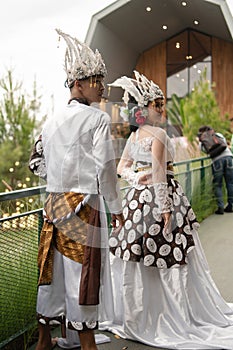 a pair of brides in white clothes standing together very intimately in a tourist park