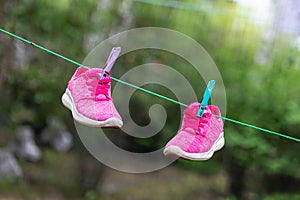 Pair of bright sport fitness sneakers hanged on clothespin at backyard after laundry outdoors. Preparartion for running training