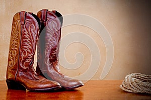 A pair of brown cowboy boots and a coil of rope photo