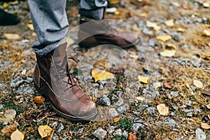 A pair of brown hiking boot in autumn forest. Soft focus on boot