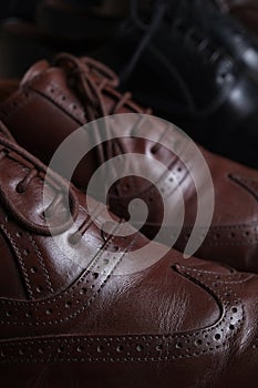 Pair of brown leather classic Brogue shoes on shelf with other shoes