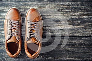 Brown leather men`s boots on wooden background top view with copy space