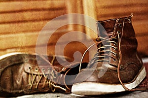 Pair of brown used and old boots on wooden background