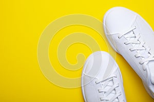 Pair of casual shoes on yellow background. Top view of stylish sneakers on color background with place for text