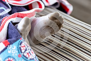 Pair of child feet in dirty stained white socks. Kid soiled socks while playing outdoors. Children clothes bleaching and