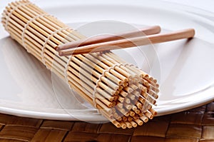 A pair of chopsticks and a sushi rolling mat
