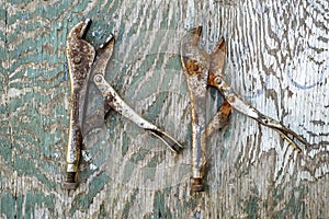 Pair of chrome rusted grip pliers on a pelling paint plywood