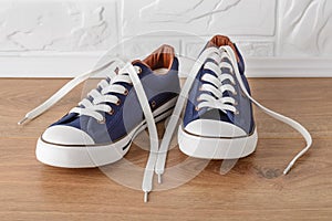 Pair of classic blue sneakers or gumshoes with white shoe laces on a floor. Comfortable shoes for fitness and sport