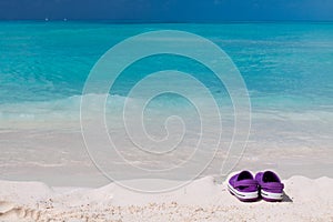 Pair of colored sandals on a white sand beach