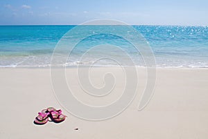 Pair of colored sandals on a white sand beach