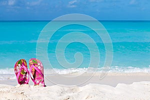 Pair of colored sandals on a white sand beach