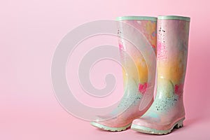 Pair of colorful rubber boots on pink background. Space for text