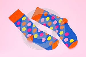 Pair of colorful socks on light pink background, flat lay