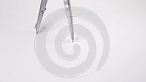 Pair of compasses drawing circle on a paper