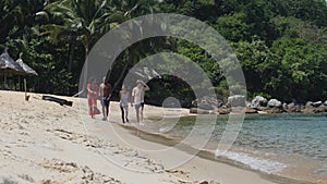 Pair of couples walking in the white sand beach on summer day at exotic island