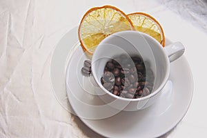 Pair Cup and saucer, coffee beans, slices of dried orange on silver table