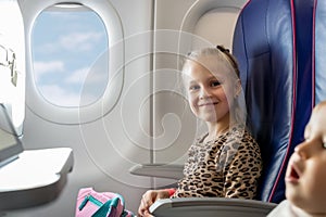 Pair of cute little adorable sibling brother and sister traveling by plane. Boy and girl sit inside aircraft during flight.