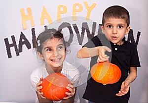 Pair of cute siblings posing near a spooky Halloween-themed background