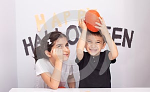 Pair of cute siblings posing near a spooky Halloween-themed background