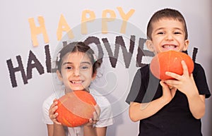 Pair of cute siblings posing near a spooky Halloween-themed background