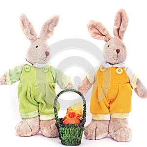 A pair of cute toy soft hares and a basket of Easter eggs