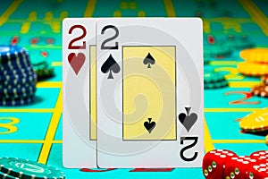 A pair of deuces playing cards on green background of a gaming table in a casino. Close up of playing cards, chips