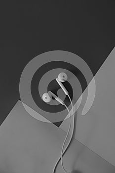 Pair of in-ear headphones on dark black and white background.