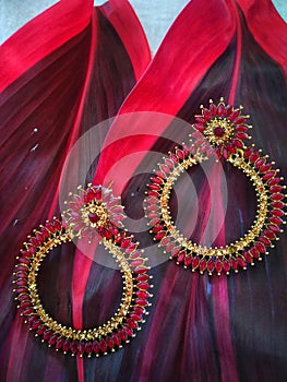 Pair of ear rings in red and golden color on two red leafs