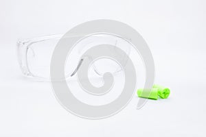 Pair earplugs against noise in different colors and plastic transparent protective work goggles.