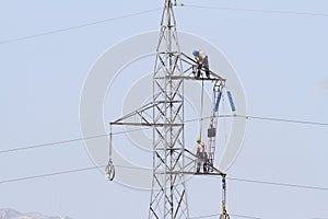 Workers over a high tension tower making reparations.