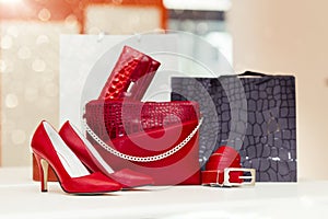 Pair of elegant leather women shoes with high heels and woman purse in the background on the shelf at the shoe store