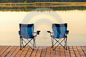 A pair of empty chairs stand on a wooden pier