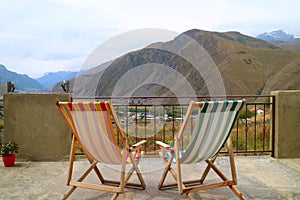 Pair of empty deck chairs at the veranda against beautiful mountain view