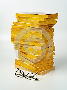 Pair of eyeglasses and stack of paperback books