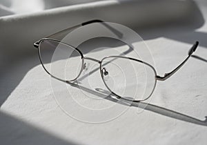 A pair of eyeglasses with thin metal frames rests on a textured
