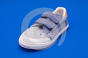 Pair of fashion denim baby shoes for the toddlers feet. Kids sneakers isolated on blue background.