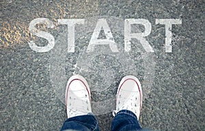 Pair of feet on  asphalt road with print of the word start