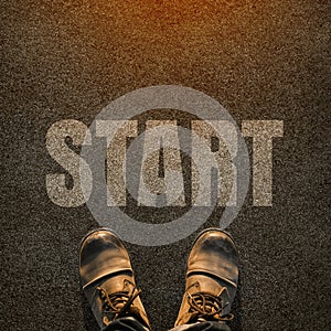 A pair of feet on a tarmac road with white print of the word sta