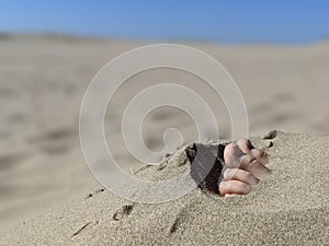 A pair of feet and toes sticking out of beach sand no grass photo