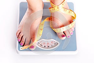 A pair of female feet standing on a bathroom scale