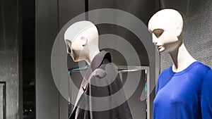 Pair of female mannequins in a store window wearing dark clothes. Two women.