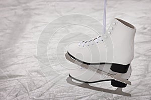 Pair of figure skates hanging over ice, space for text