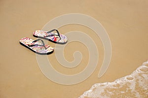 A pair of flip flops on the beach sand, Summer back concept.