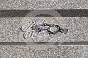 Pair of flip flops padlocked to a steel chain