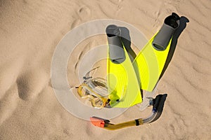 Pair of flippers, snorkel and diving mask on sandy beach, flat lay. Space for text